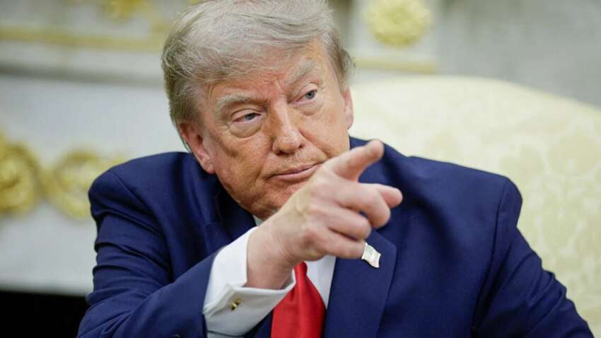 Дональд Трамп у синьому костюмі з червоною краваткою вказує пальцем