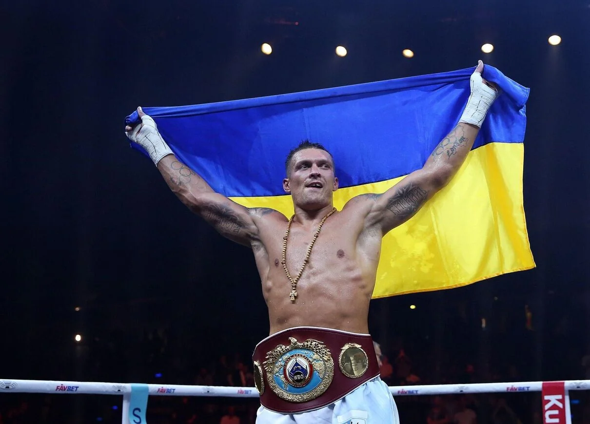 Олександр Усик святкує з прапором України та чемпіонським поясом на рингу