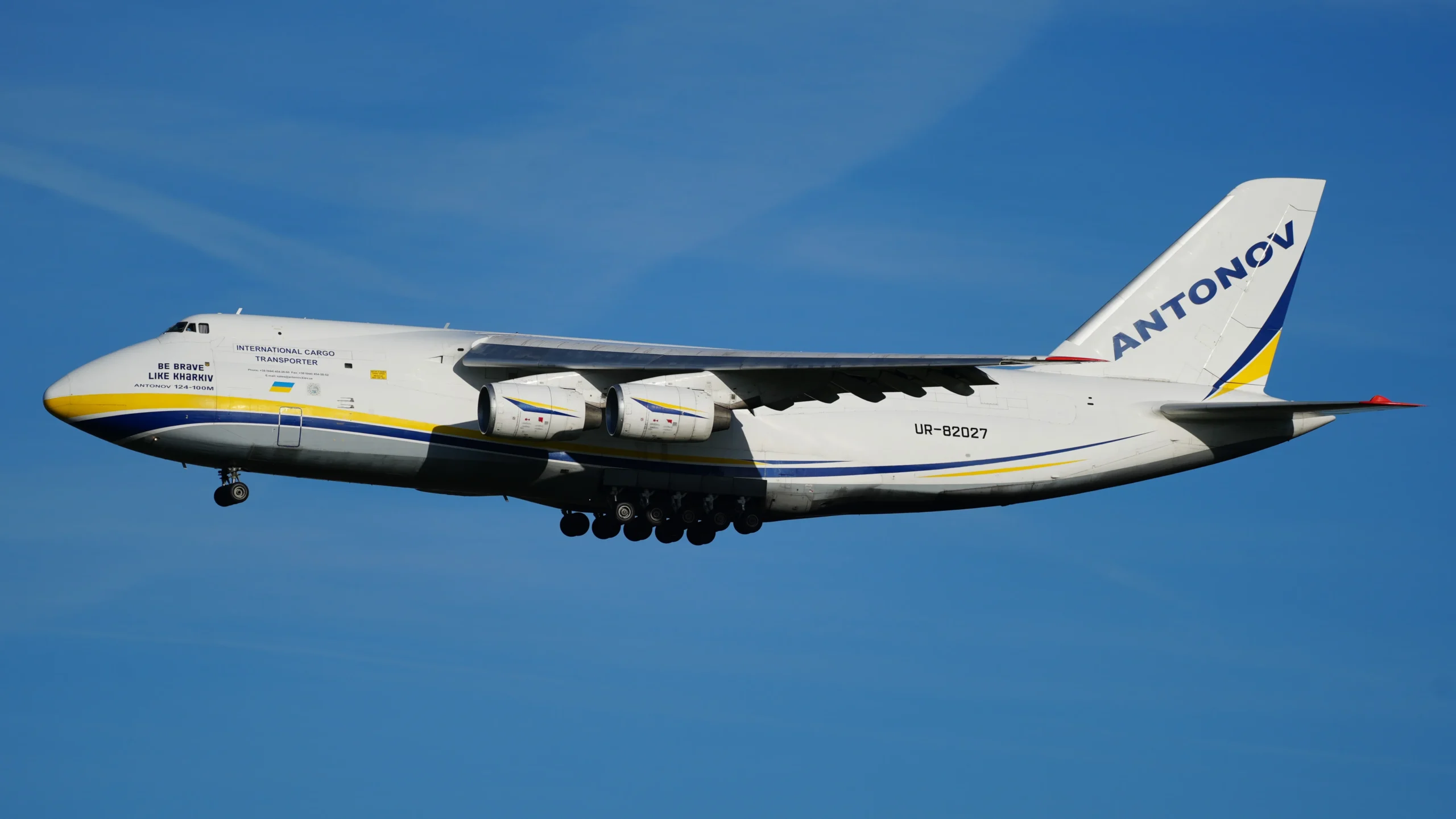 Білий вантажний літак Antonov An-124 у польоті на тлі синього неба