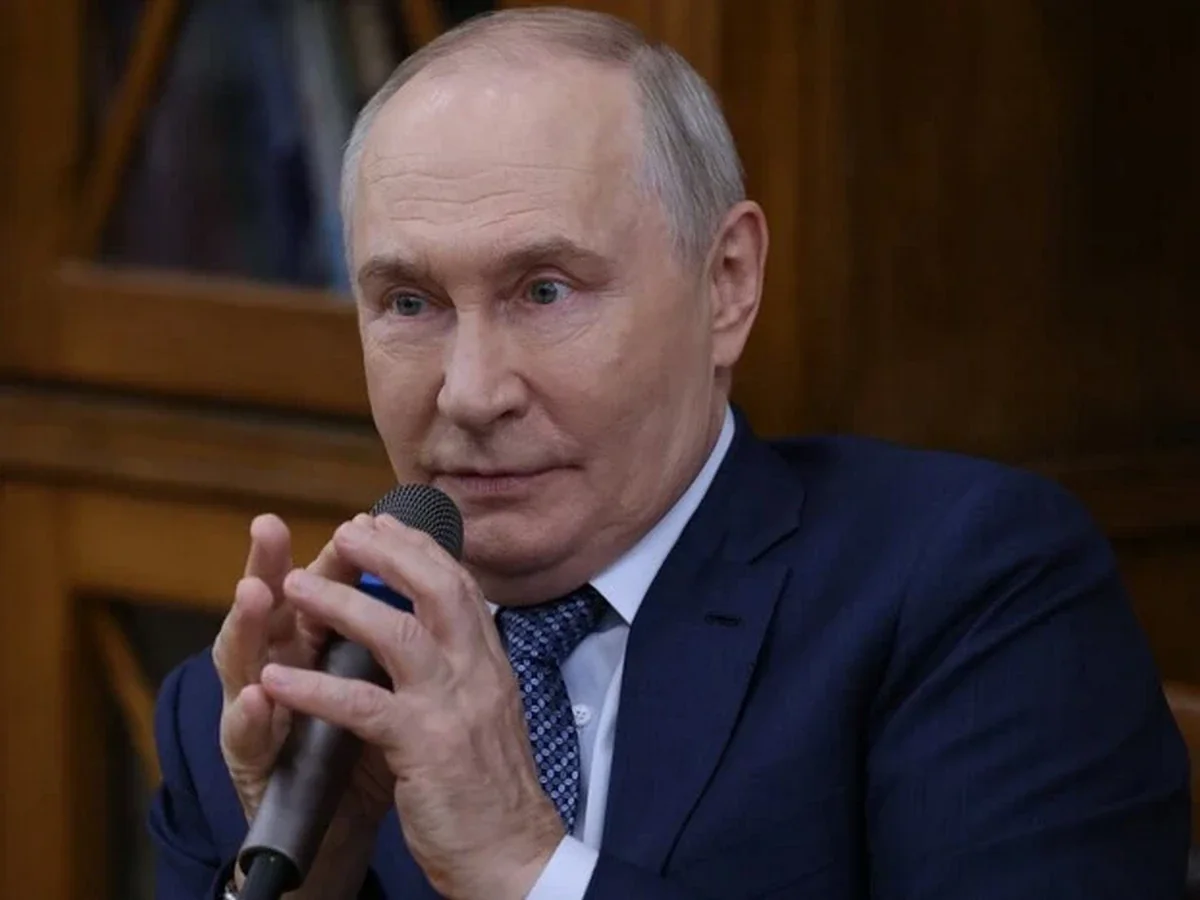 Володимир Путін у костюмі говорить у мікрофон на тлі дерев’яних панелей