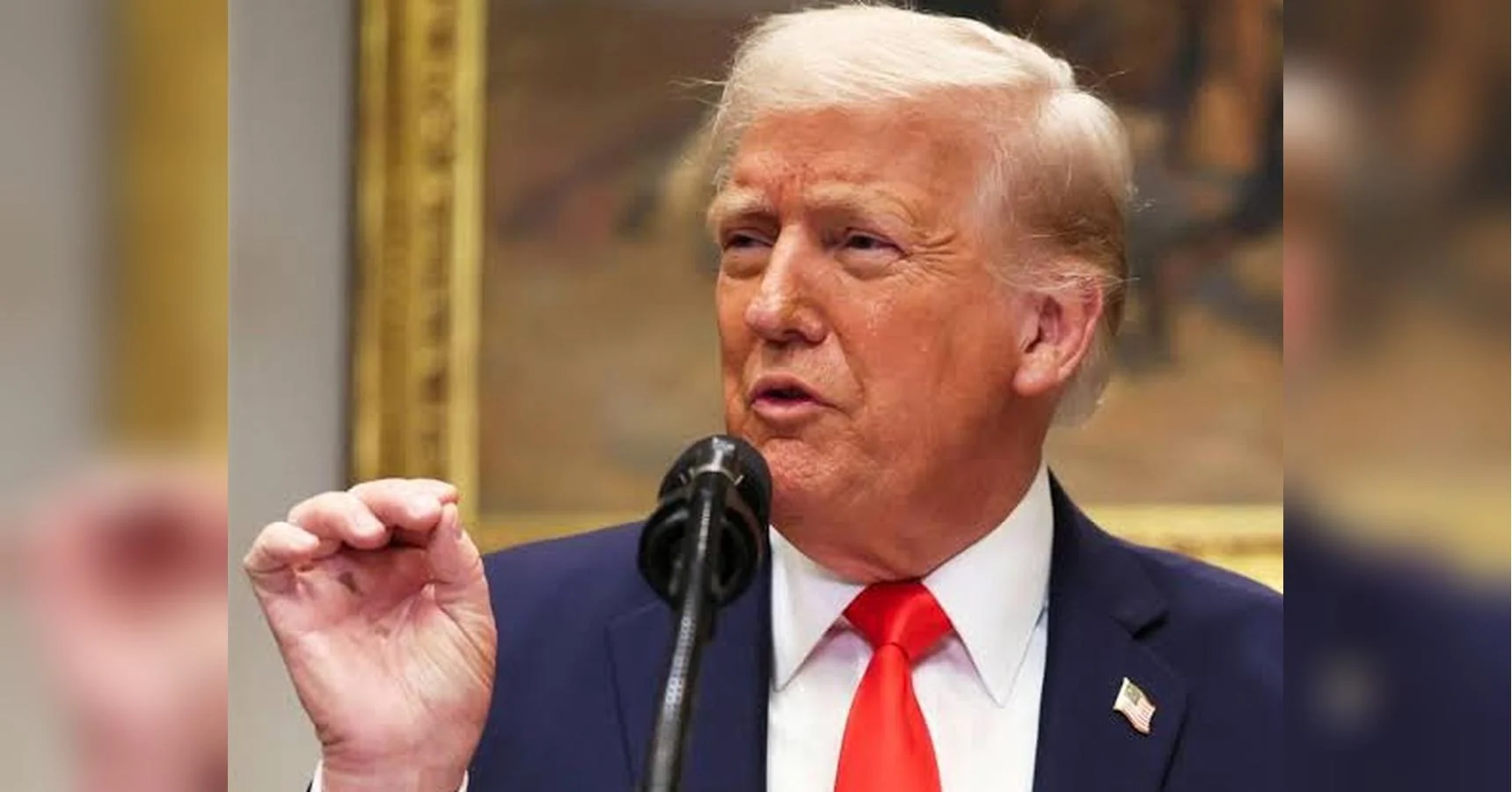 Дональд Трамп у синьому костюмі говорить у мікрофон, жестикулюючи рукою